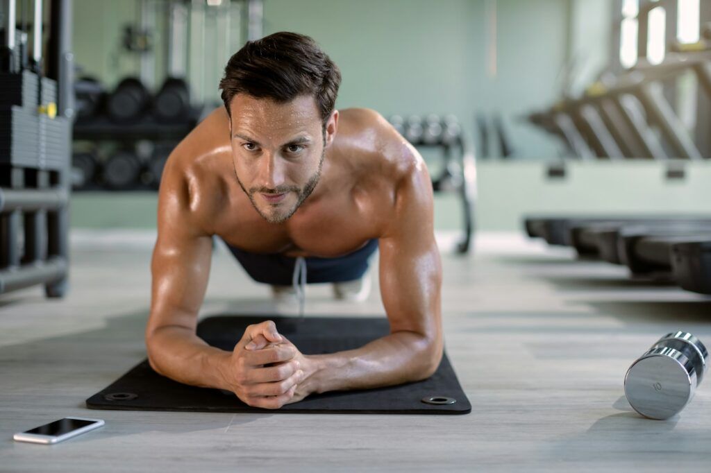 Male athlete in plank pose exercising at health club.