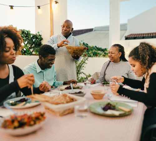 Happy African family dining together on house patio - Family Gatherings concept
