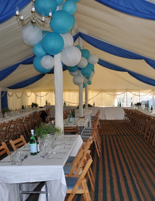 Wedding reception held in a huge tent decorated with balloons and blue and white curtains.
